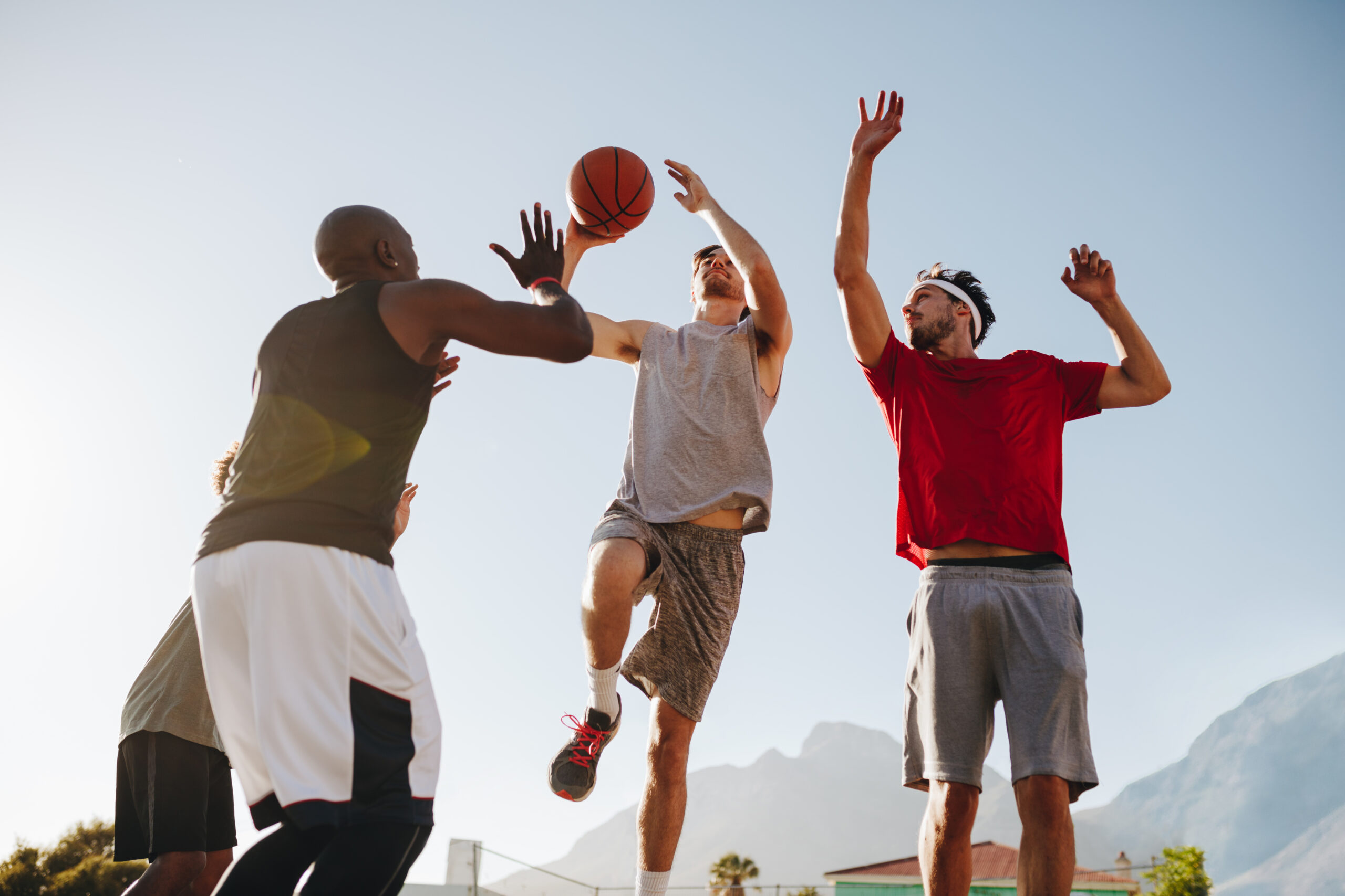 Men playing basketball game on a sunny day. Men practicing basketball dribbling skills.